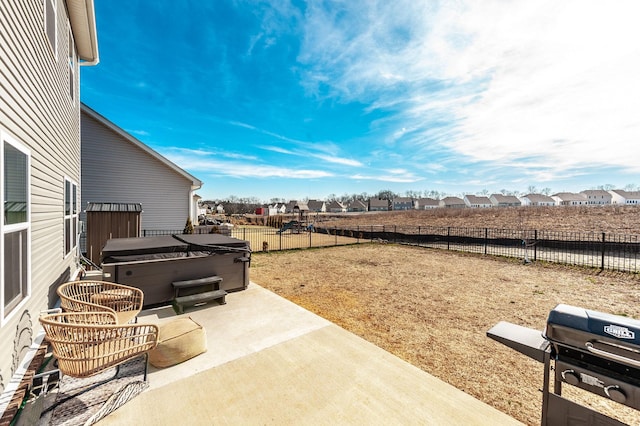 view of patio featuring area for grilling, a fenced backyard, a residential view, and a hot tub