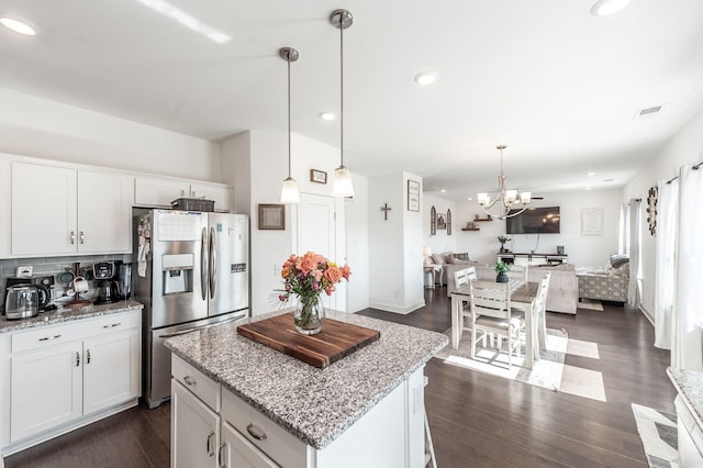 kitchen with open floor plan, decorative light fixtures, white cabinets, and stainless steel fridge with ice dispenser