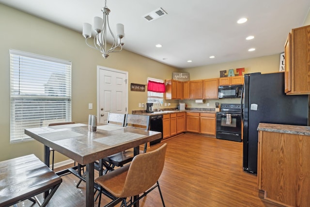 kitchen with black appliances, plenty of natural light, wood finished floors, and visible vents