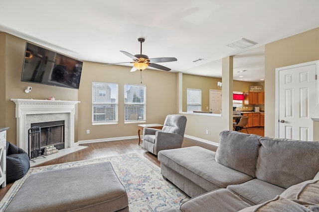 living area featuring visible vents, wood finished floors, a high end fireplace, and baseboards