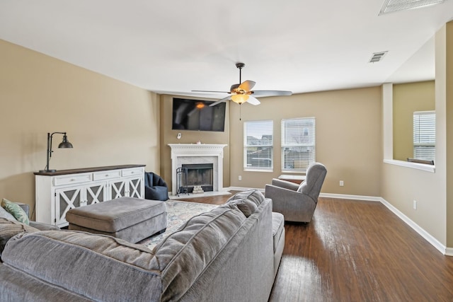 living room featuring baseboards, a premium fireplace, visible vents, and dark wood finished floors