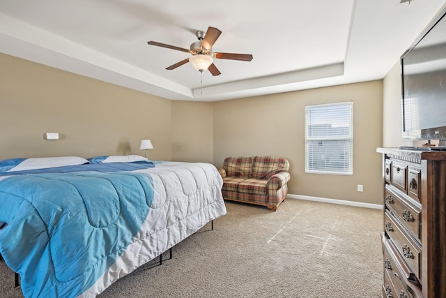 bedroom featuring a raised ceiling, light carpet, ceiling fan, and baseboards