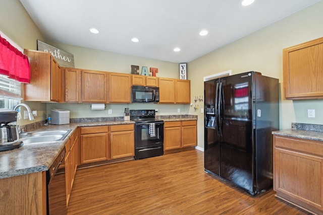 kitchen with black appliances, recessed lighting, a sink, and wood finished floors