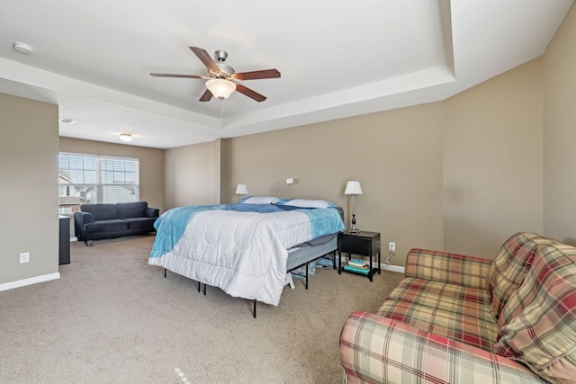 bedroom with carpet, baseboards, a raised ceiling, and a ceiling fan