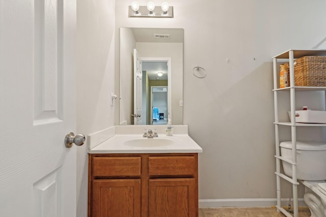 half bath featuring toilet, baseboards, visible vents, and vanity