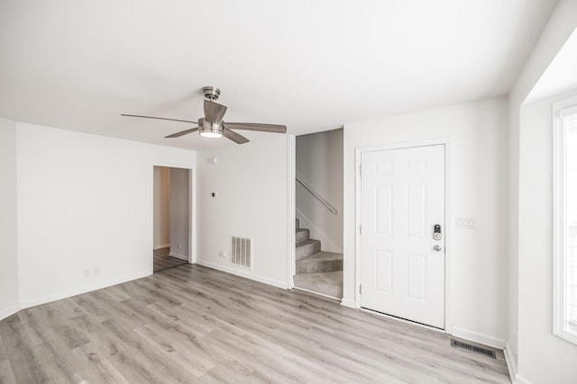 unfurnished room featuring stairway, visible vents, and light wood-style floors