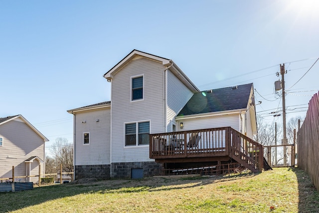 rear view of property featuring a deck, fence, roof with shingles, stairway, and a lawn