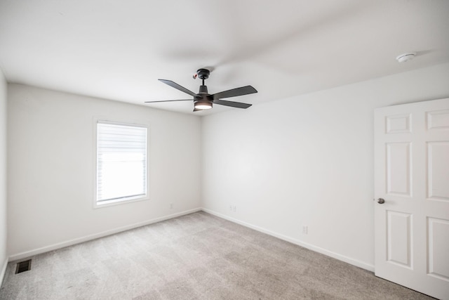 empty room with light carpet, a ceiling fan, visible vents, and baseboards