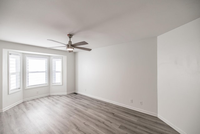 spare room featuring ceiling fan, light wood-style flooring, and baseboards