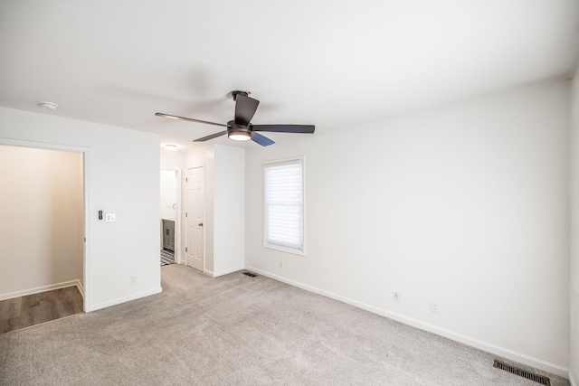 unfurnished bedroom featuring a ceiling fan, visible vents, light carpet, and baseboards