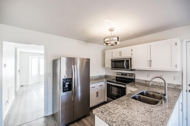 kitchen with white cabinets, stainless steel appliances, a sink, and decorative light fixtures