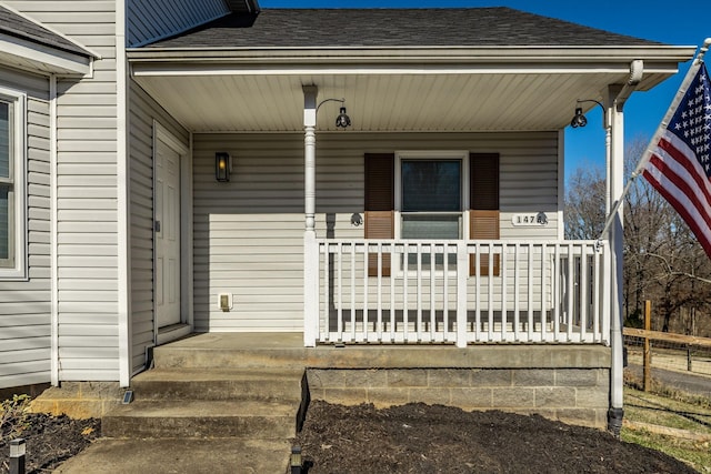 entrance to property with covered porch and roof with shingles