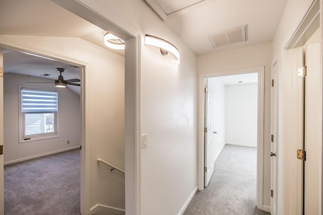 hallway featuring baseboards, visible vents, vaulted ceiling, and carpet flooring