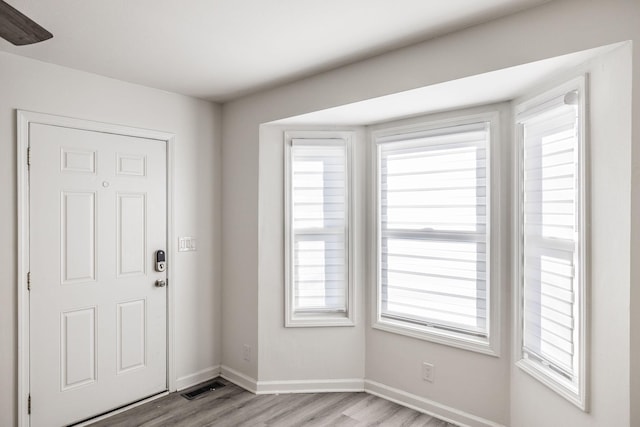 foyer featuring baseboards, visible vents, light wood-style flooring, and a healthy amount of sunlight