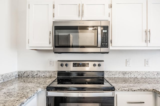 kitchen featuring light stone counters, appliances with stainless steel finishes, and white cabinetry