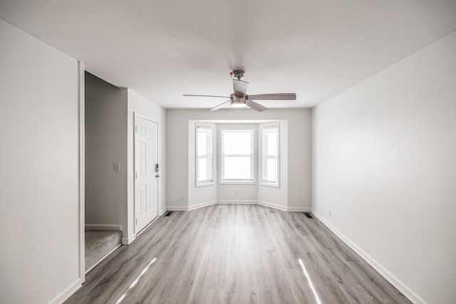 unfurnished room featuring light wood finished floors, baseboards, and a ceiling fan