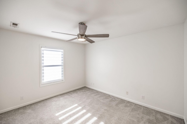 carpeted spare room with baseboards, visible vents, and ceiling fan