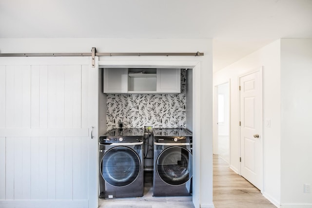 laundry room with washing machine and dryer, laundry area, light wood-style flooring, and a barn door