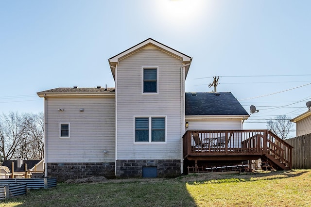 back of house featuring a shingled roof, a deck, and a yard