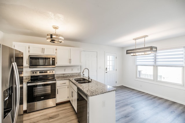 kitchen featuring white cabinets, appliances with stainless steel finishes, decorative light fixtures, a peninsula, and a sink