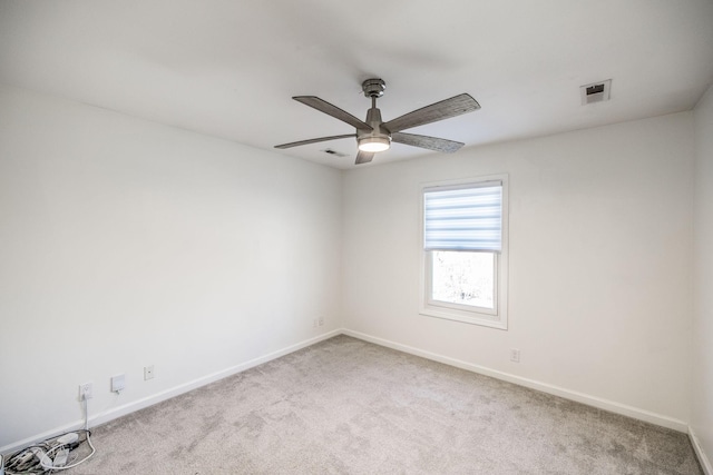 spare room with light carpet, a ceiling fan, visible vents, and baseboards