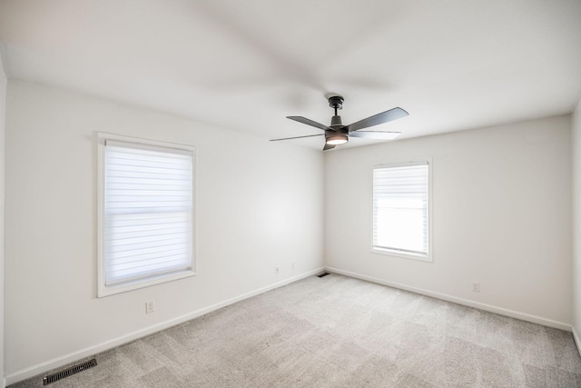 empty room featuring baseboards, visible vents, a ceiling fan, and light colored carpet