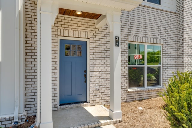 view of exterior entry featuring brick siding