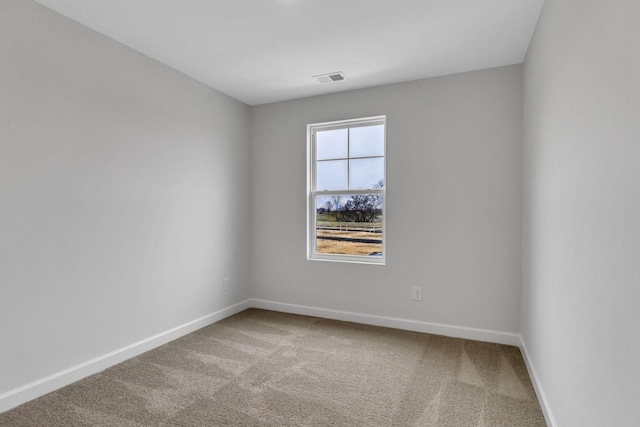 carpeted spare room with visible vents and baseboards