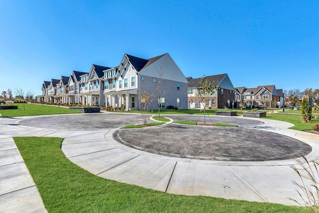 view of property's community with a residential view, curved driveway, and a lawn