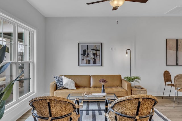 living area featuring a ceiling fan, light wood-style flooring, and baseboards