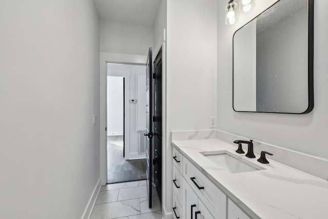 bathroom with marble finish floor, baseboards, and vanity