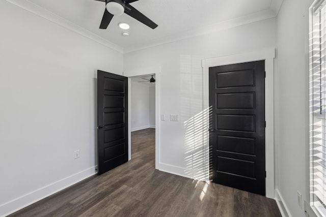 empty room featuring ornamental molding, dark wood-style flooring, a ceiling fan, and baseboards