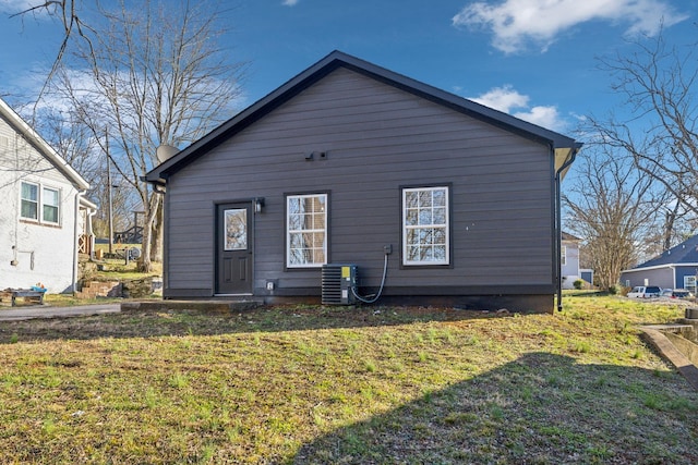 back of house with cooling unit and a lawn