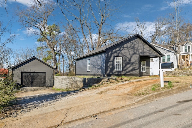 view of front of house with driveway, a detached garage, and an outbuilding