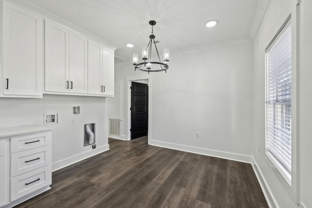 unfurnished dining area featuring ornamental molding, dark wood-type flooring, a notable chandelier, and baseboards