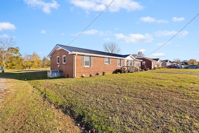 view of home's exterior with metal roof, brick siding, a lawn, and central air condition unit