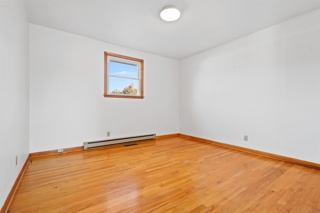 empty room with a baseboard radiator, light wood-style flooring, and baseboards