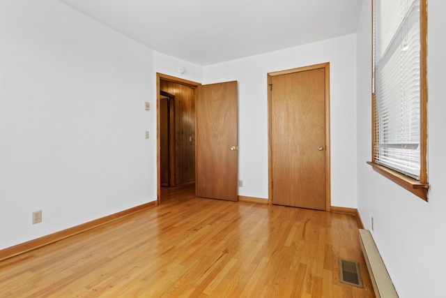 unfurnished bedroom with light wood-style flooring, visible vents, and baseboards