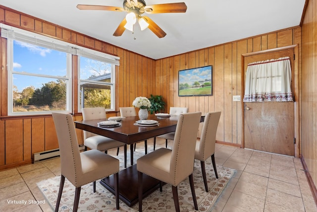 dining space featuring light tile patterned floors, ceiling fan, a baseboard heating unit, and wood walls