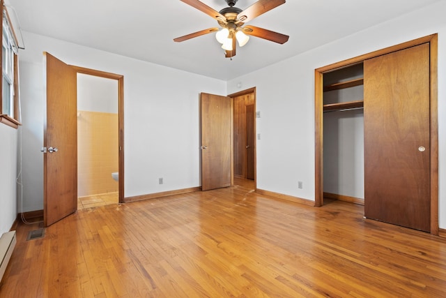 unfurnished bedroom featuring a closet, visible vents, baseboard heating, light wood-type flooring, and baseboards