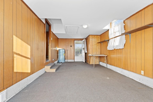 interior space featuring wood walls, attic access, and dark colored carpet