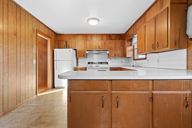 kitchen featuring electric stove, brown cabinets, light countertops, freestanding refrigerator, and extractor fan