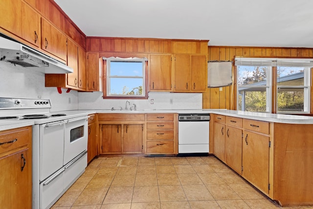 kitchen with white appliances, light tile patterned floors, light countertops, under cabinet range hood, and a sink