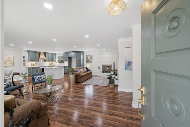 living area with baseboards, dark wood finished floors, crown molding, a fireplace, and recessed lighting