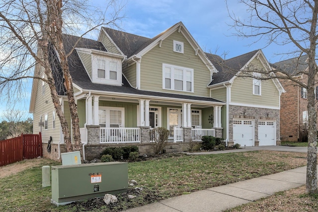 craftsman inspired home with a porch, an attached garage, stone siding, driveway, and roof with shingles