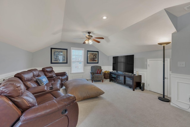 living room with light colored carpet, visible vents, a ceiling fan, wainscoting, and vaulted ceiling