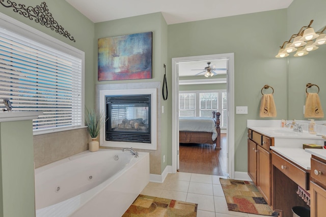 ensuite bathroom with a tiled fireplace, ensuite bath, a tub with jets, tile patterned flooring, and vanity