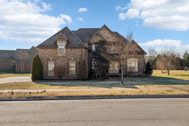 french country inspired facade featuring a front lawn and brick siding