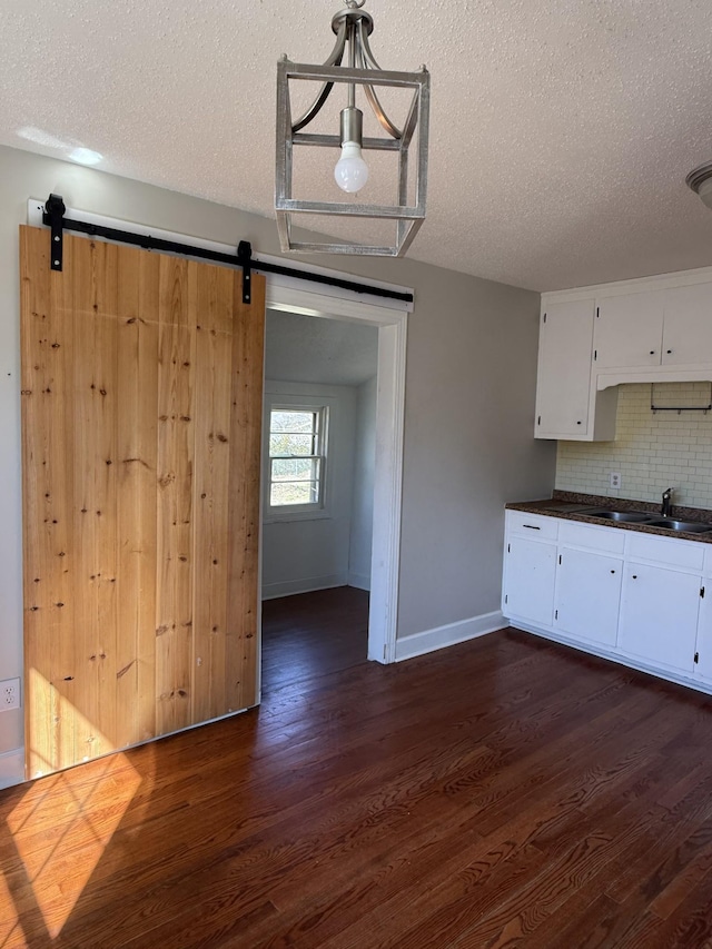 kitchen with dark wood-style floors, dark countertops, a barn door, and a sink