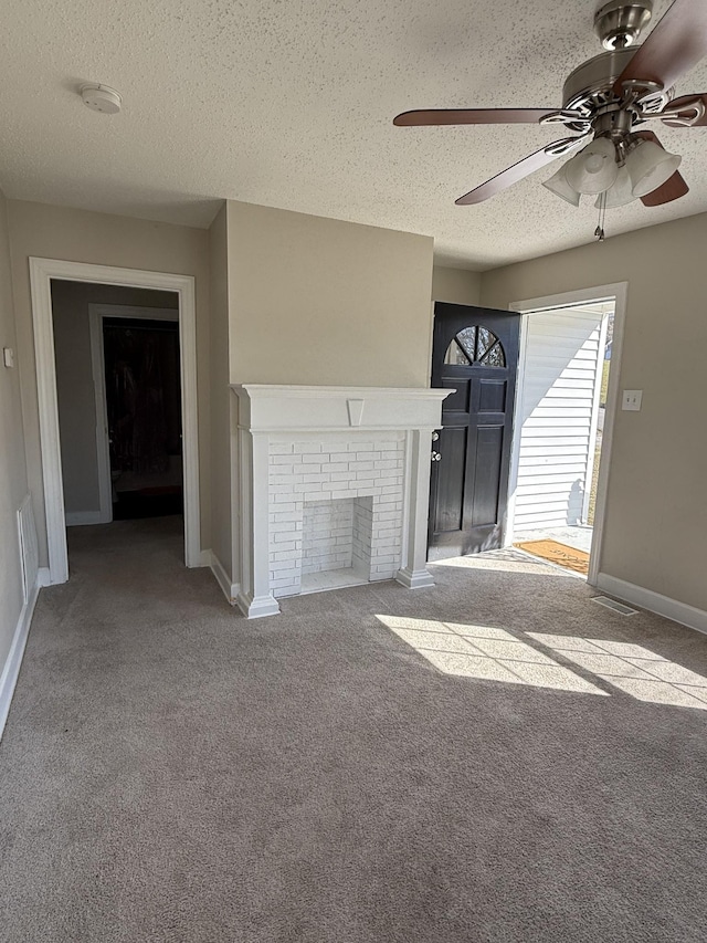 unfurnished living room with a brick fireplace, carpet, baseboards, and a textured ceiling